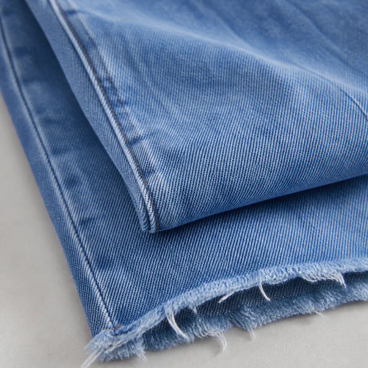 Women's jeans raw hem, denim surface and side seam close-up